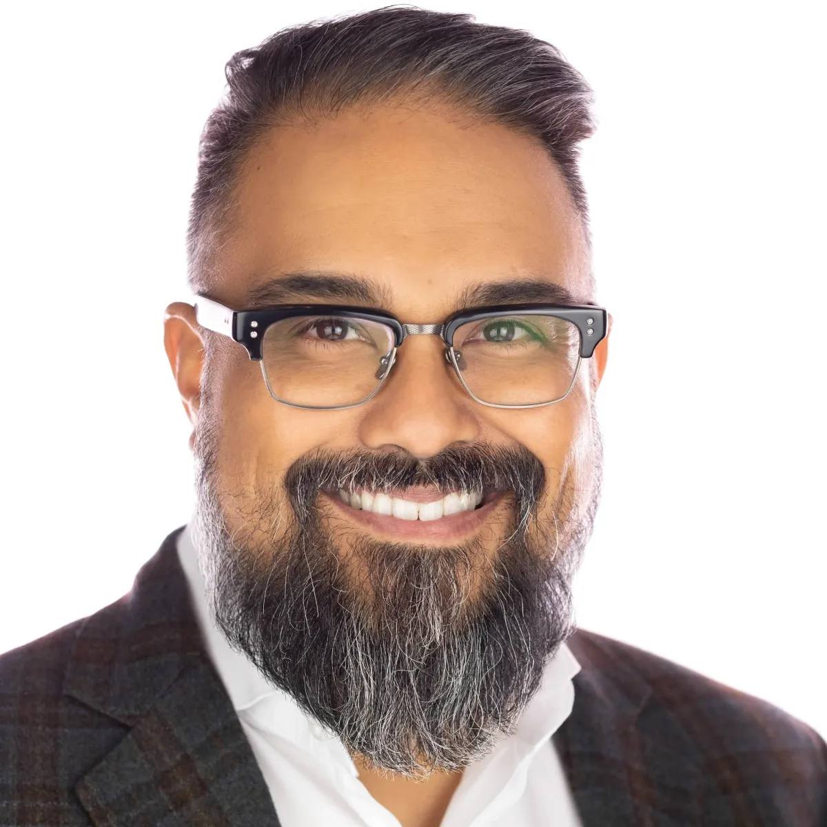 Headshot of a man with glasses and a greying beard, smiling, in a plaid blazer and white shirt, on a white background